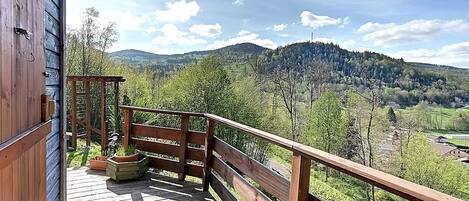 A wooden deck with a railing overlooking a mountainous landscape.