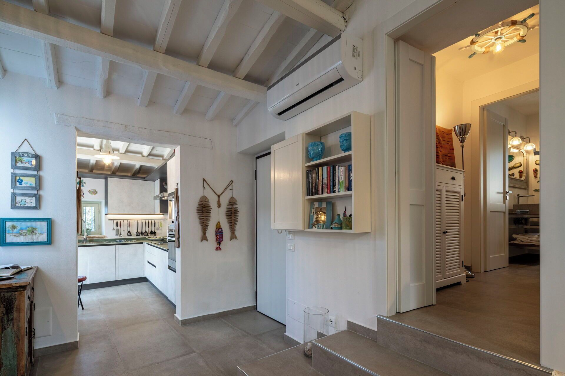 A modern interior with a kitchen, open shelving, and a staircase.