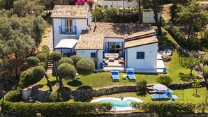 Una villa de estilo mediterráneo con piscina, tumbonas y un muro de piedra.