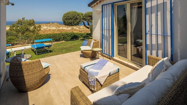 Un patio al aire libre con mobiliario de mimbre, una piscina y vistas panorámicas.
