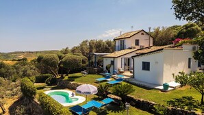 Una villa con piscina, mobiliario de exterior y jardín.