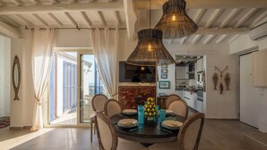 Un comedor con una mesa redonda, sillas, un televisor y vistas al exterior.