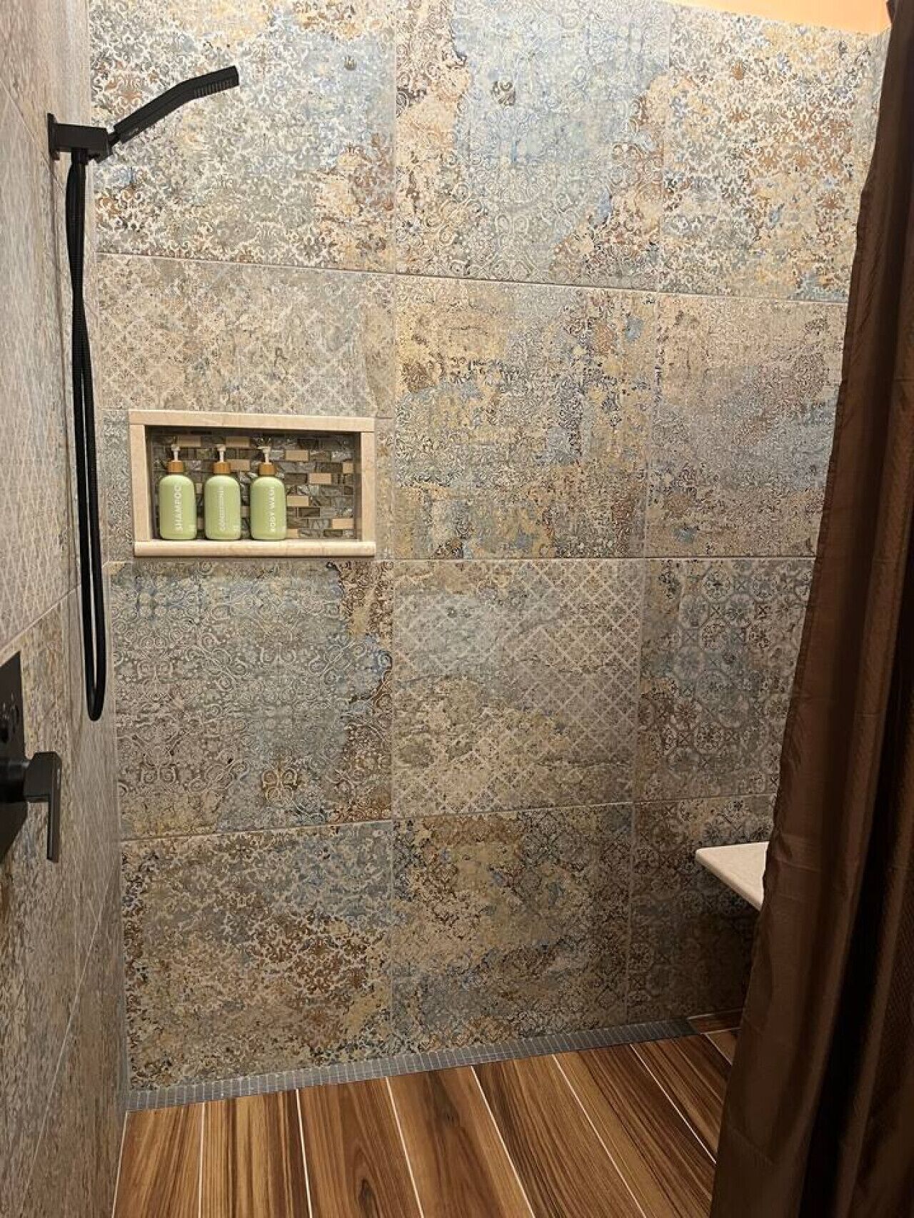 Een douche met een houten vloer, douchekop en een plank met toiletartikelen.