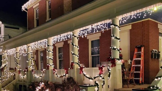 Una casa de dos pisos con un porche decorado con luces y guirnaldas.