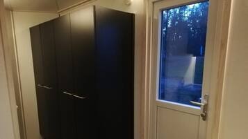 A room with a large wardrobe, a small table, and a window with a view of trees.