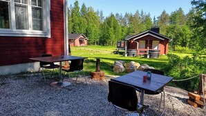 A red building with a gravel patio, two tables, and chairs.