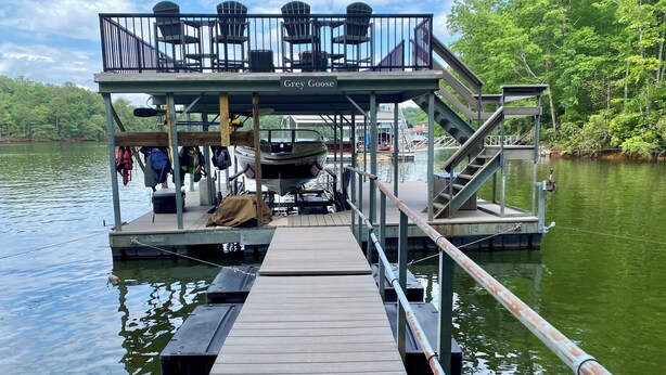 A dock with a covered seating area and a boat.