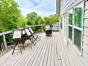A wooden deck with outdoor furniture, a railing, and a view of trees.