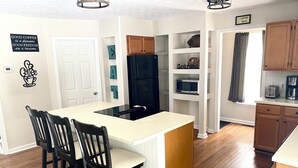 A modern kitchen with a central island, wooden cabinets, and a built-in microwave.