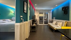 Quarto de hotel moderno com cama, escrivaninha, sofá e guarda-roupa com porta deslizante.
