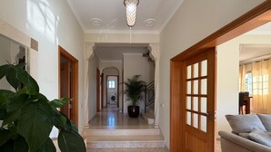 A hallway with a potted plant, a sofa, and a staircase leading to another room. - Villa Sao Miguel (Albufeira)