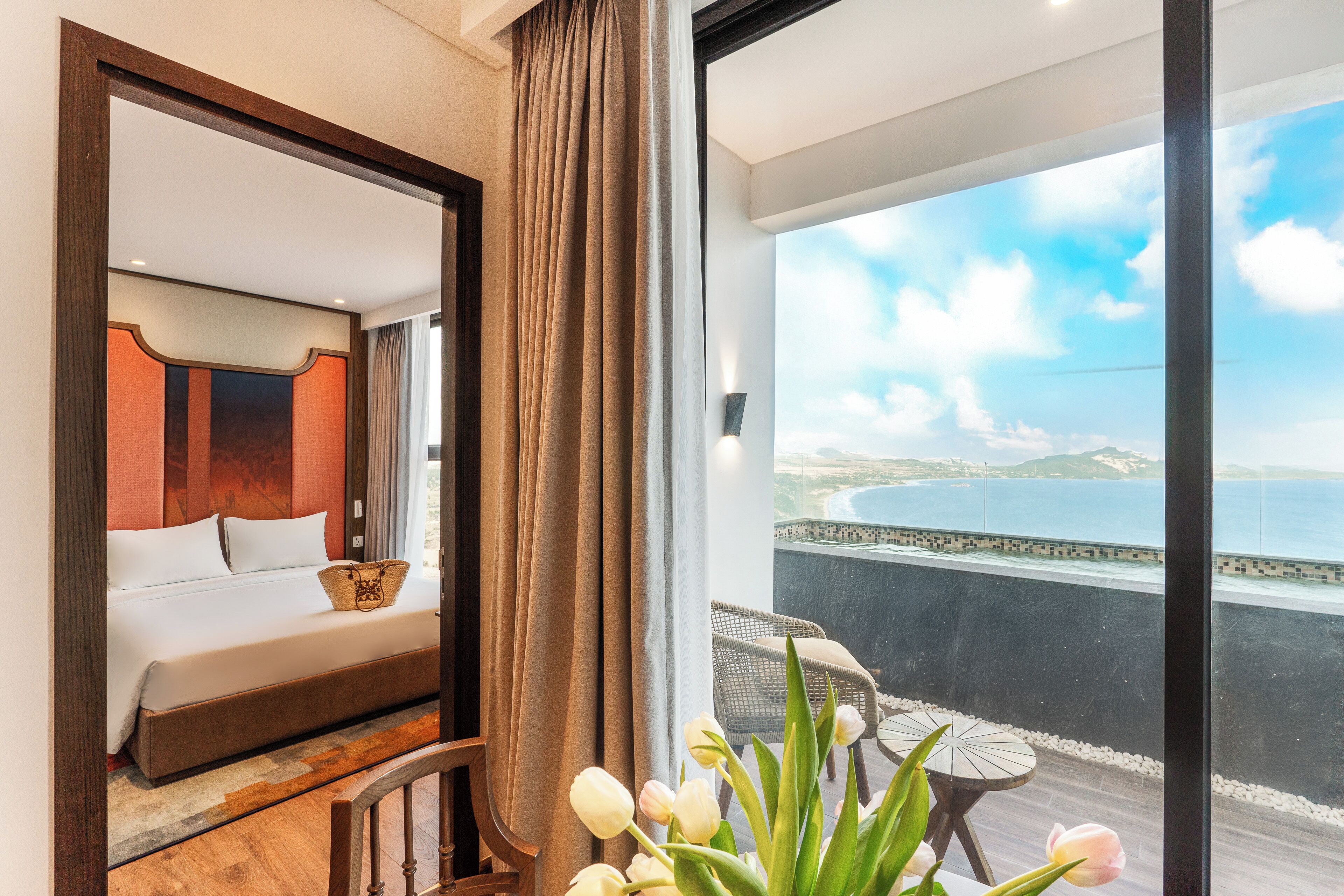 Un dormitorio con una cama grande, vistas al mar y un balcón con mesa y sillas.