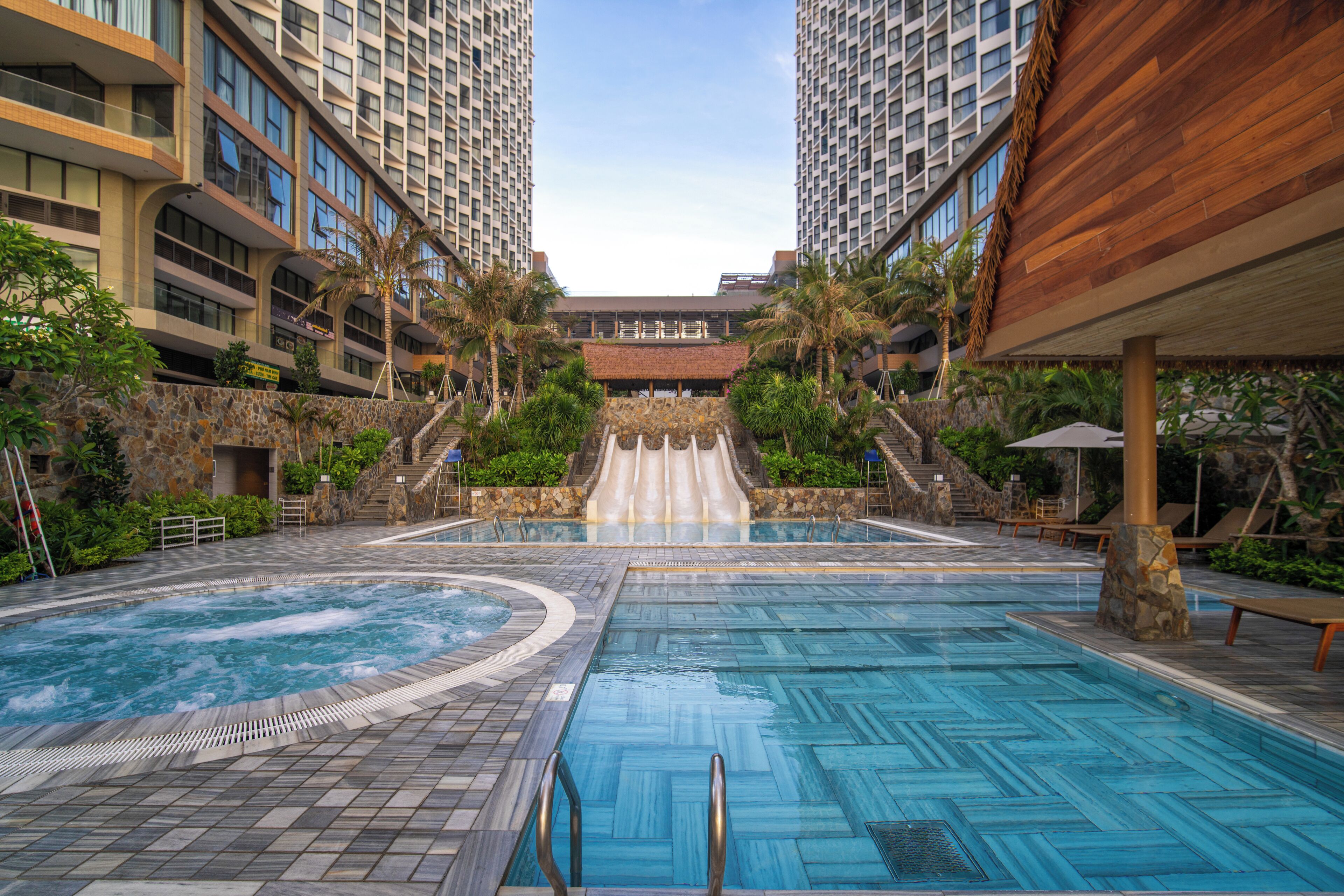 A hotel pool area with a hot tub, a slide, and a view of high-rise buildings.