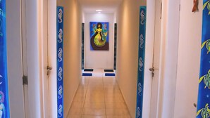 Un pasillo con suelo de baldosas, felpudos negros en la entrada y puertas a ambos lados.
