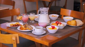 Una mesa de desayuno con diversas opciones de comida y bebidas, como tostadas, fruta y una jarra de leche.