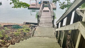 Una escalera de madera que lleva a un muelle sobre el agua, rodeado de vegetación.