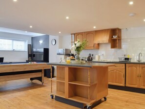 Une cuisine moderne avec des meubles en bois, un four encastré et un coin repas comprenant une table et des chaises.