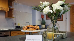 A kitchen counter with pastries, a vase with flowers, a pitcher of juice, and a thank you card. - 2 bedroom accommodation in Carterton (Carterton)