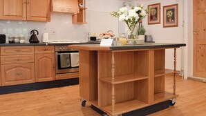 A kitchen with wooden cabinets, a central island, and a built-in oven. - 2 bedroom accommodation in Carterton (Carterton)