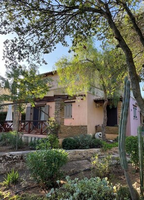 Una casa rústica con fachada de piedra, terraza de madera y un jardín de cactus.