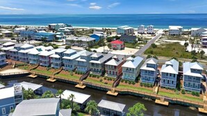 Uma área residencial costeira com casas ao longo de um canal, ligadas por uma ponte.