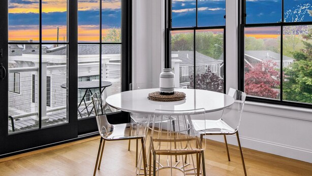 Un comedor moderno con una mesa redonda y sillas, ventanas amplias con vista a la ciudad y una lámpara en el techo.