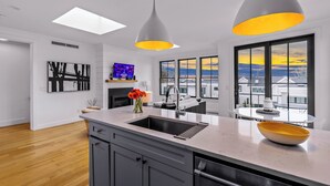 Una cocina moderna con una isla central, un lavamanos empotrado e iluminación colgante.
