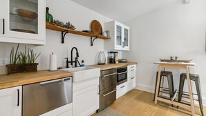 Et moderne køkken med hvide skabe, rustfrie stålapparater og en træbordplade.