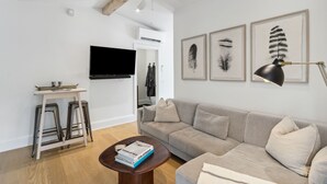 En moderne stue med sofa, sofabord med bøger, fjernsyn og billeder af fjer på væggen.
