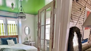 A room with a bed, a mirror, a chandelier, and a green wall. - Cute & Artsy Condo 1mi from Crystal lake, & 7mi from Frankfort (Benzonia)