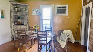 A dining area with a wooden table and chairs, a vase with flowers, and a bookshelf. - Cute & Artsy Condo 1mi from Crystal lake, & 7mi from Frankfort (Benzonia)