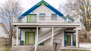 A two-story house with a balcony, a staircase, and a front porch. - Cute & Artsy Condo 1mi from Crystal lake, & 7mi from Frankfort (Benzonia)
