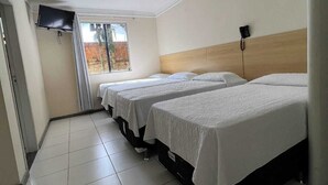 Habitación de hotel con dos camas, un televisor montado en la pared y una ventana con vistas al exterior.