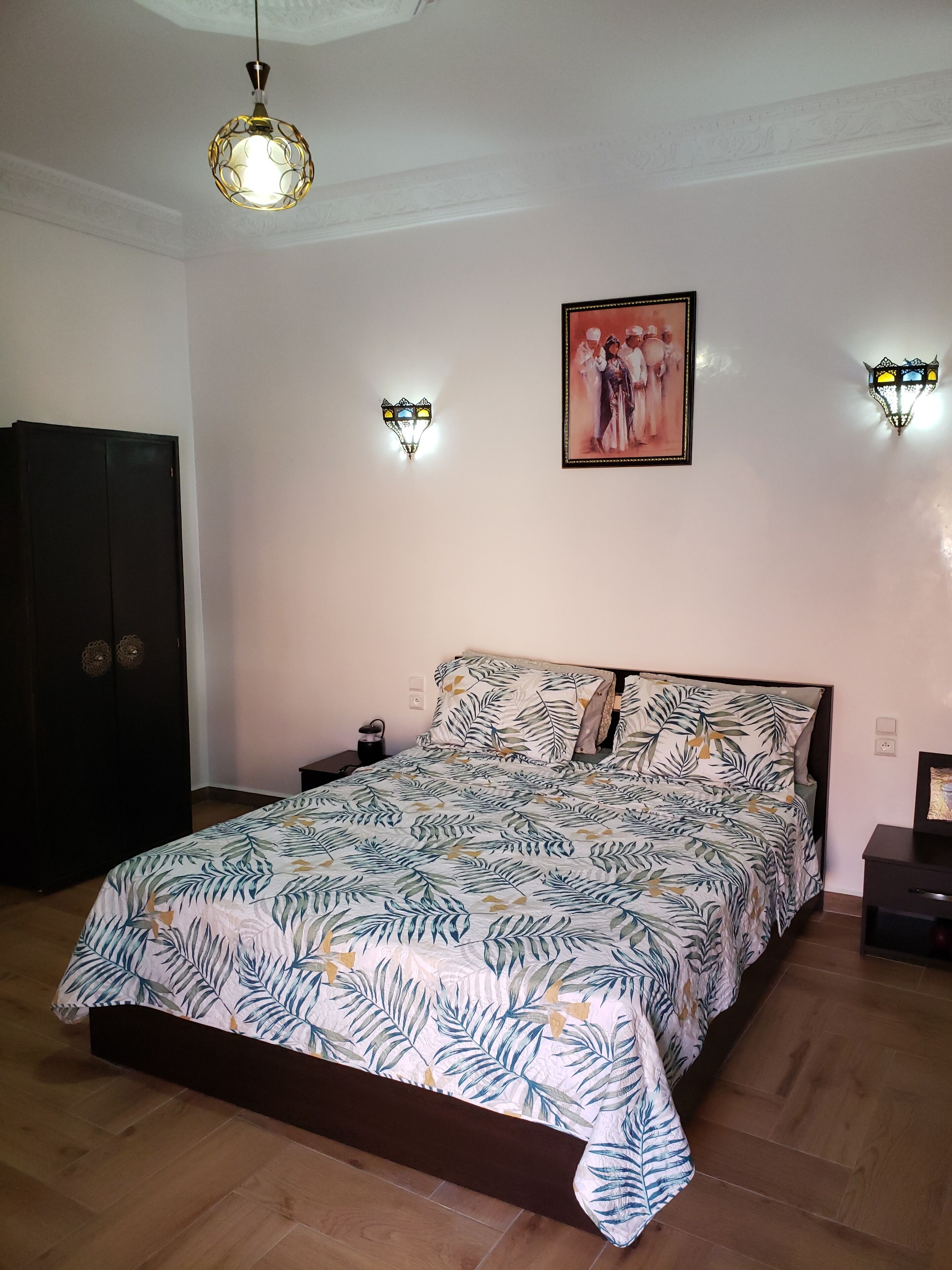 A bedroom with a bed, a wardrobe, and two wall-mounted lights.