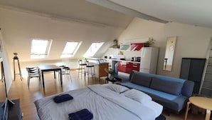 Amplio dormitorio tipo loft con una cama grande, un sofá y un comedor.