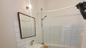 Un baño con lavamanos blanco, espejo, inodoro y bañera.