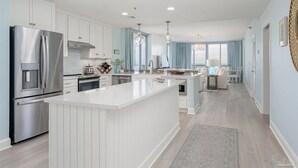 Une cuisine moderne avec des meubles blancs, des appareils en acier inoxydable et un îlot central.