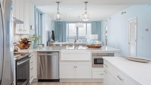 Une cuisine moderne avec des meubles blancs, des appareils en acier inoxydable et un îlot central.