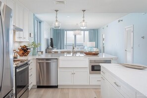 A modern kitchen with white cabinetry, stainless steel appliances, and a central island.