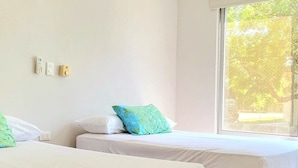 A hotel room with two beds, a window with a view of trees, and a wall-mounted phone.
