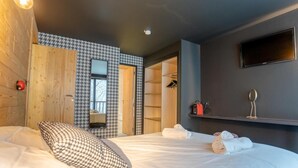 Quarto de hotel moderno com uma cama grande, parede com padrão xadrez de houndstooth, espelho e televisão fixada na parede.