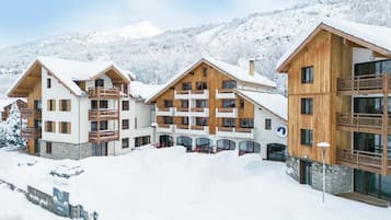 En snötäckt semesteranläggning med trähus, balkonger och en fantastisk utsikt över de omgivande bergen.
