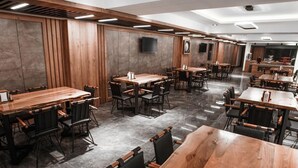 A spacious restaurant with multiple wooden tables and black chairs, arranged in a modern layout. - MAYBEN HOTEL  (Çaykara)