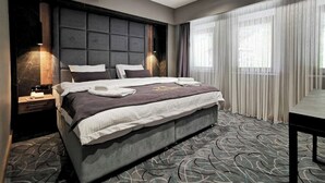 A modern hotel room with a large bed, a bedside table, a desk, and a view of the outdoors through sheer curtains. - MAYBEN HOTEL  (Çaykara)