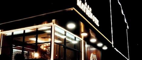 A hotel with a modern design, featuring a prominent illuminated sign and a well-lit entrance.