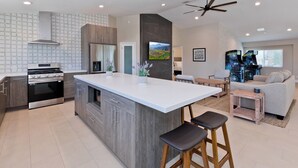 A modern kitchen with a central island, built-in appliances, and a dining area with a sofa and table.