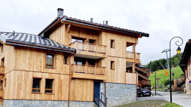 A multi-story wooden chalet with balconies, stone foundation, and a ski lift in the background. - 50m from ski slopes, 1st floor, view resort, balcony, tv, 86m², Montalbert (La Plagne)