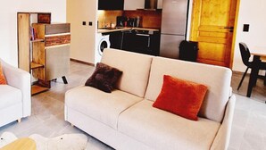 A modern living room with two sofas, a coffee table, and a bookshelf. - 50m from ski slopes, 1st floor, view resort, balcony, tv, 86m², Montalbert (La Plagne)
