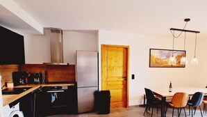 A compact kitchen with a refrigerator, stove, and sink. There is a dining area with a table and chairs, and a window with curtains. - 50m from ski slopes, 1st floor, view resort, balcony, tv, 86m², Montalbert (La Plagne)