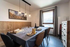 A dining area with a table set for a meal, a bottle of wine, and a scenic mountain view through the window. - 50m from ski slopes, 1st floor, view resort, balcony, tv, 86m², Montalbert (La Plagne)